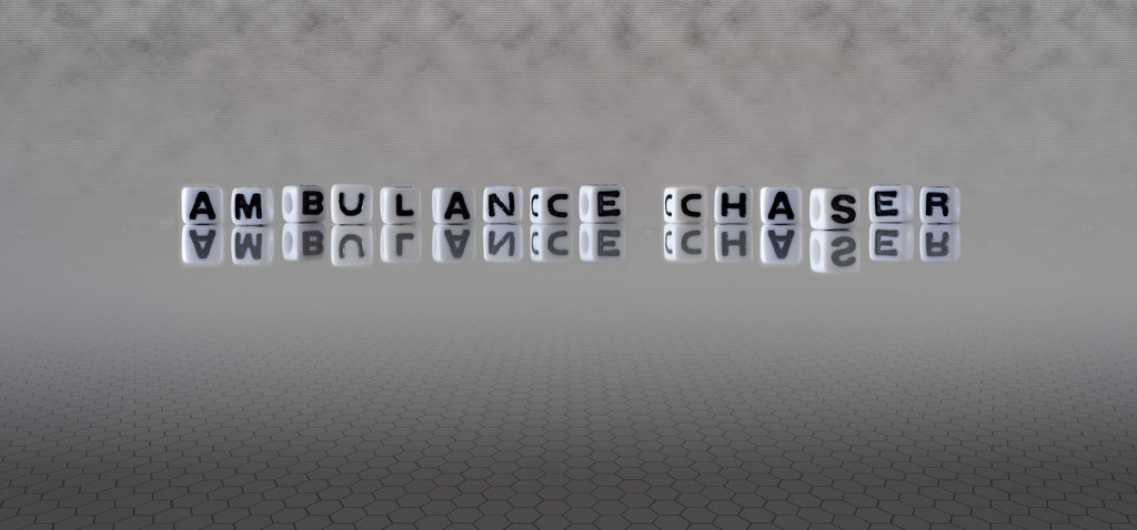 ambulance chaser word or concept represented by black and white letter cubes on a grey horizon background stretching to infinity