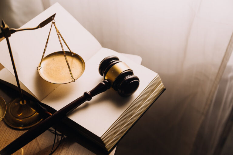 Justice and law concept.Male judge in a courtroom with the gavel, working with, computer and docking keyboard, eyeglasses, on table in morning light