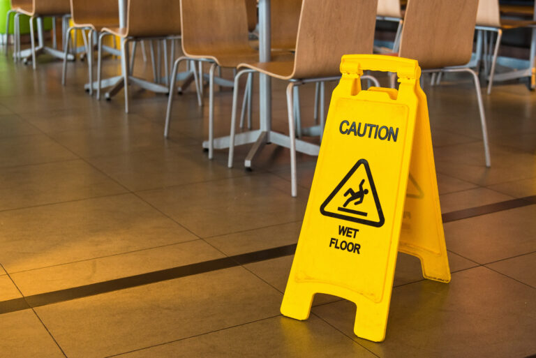 Yellow sign that alerts for wet floor in the restaurant.Thailand