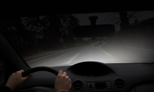 Car driving at night on a Texas road with headlights on